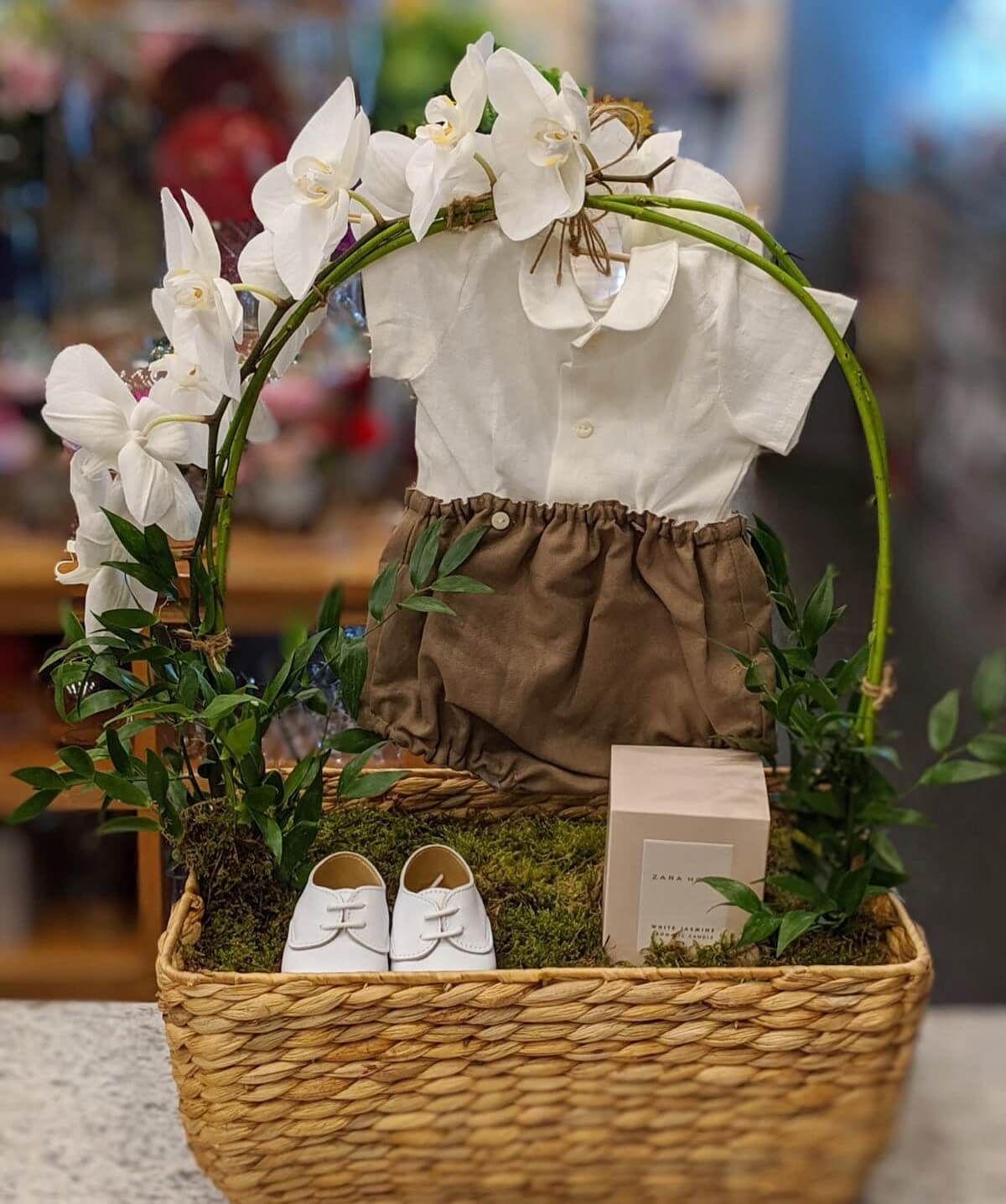 Customised gift in a basket with baby clothes flowers and gifts